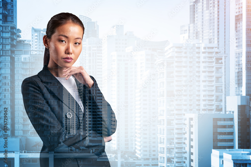 Attractive young Asian business woman in suit with hand on chin thinking how to succeed, new career opportunities, MBA. Bangkok on background. Double exposure. Attractive young Asian business woman in suit with hand on chin thinking how to succeed, new career opportunities, MBA. Bangkok on background. Double exposure.