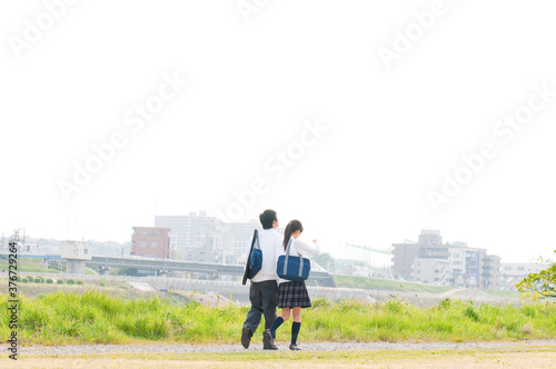 河川敷を歩く高校生カップル © Paylessimages