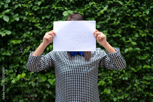 An Asian woman is standing with a white paper over her face. Able to put text for advertising media