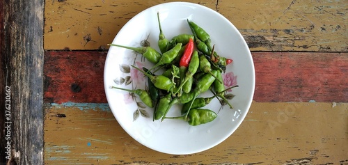 Bird's eye chilies on a white plate. On an aestethic wooden table background. Flat lay photos