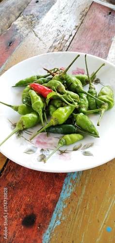 Bird's eye chilies on a white plate. On an aestethic wooden table background. Flat lay photos