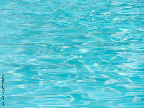 Shiny bright blue water surface in the swimming pool with waves. © ersoy