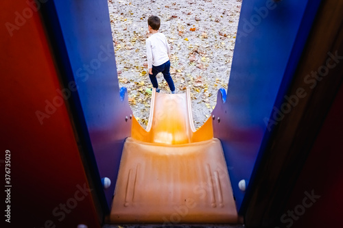 Child sliding down a slide  seen from the back from above.