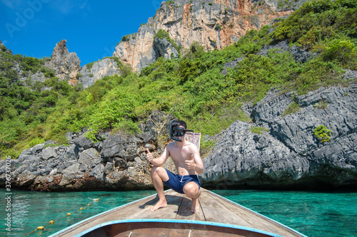 An active man on thai traditional longtail Boat is ready to snorkel and dive, Phi phi Islands, Thailand