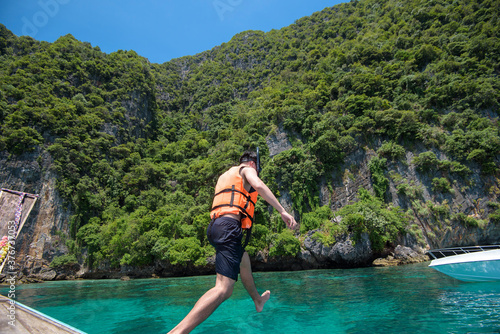 An active man on thai traditional longtail Boat is ready to snorkel and dive, Phi phi Islands, Thailand © tonefotografia