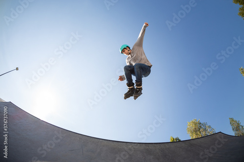 boy with inline skates, rollerblade, doing a jump in a skate park