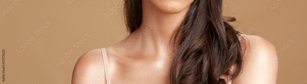 Women's neck, shoulders and chin with long brown hair against dark tan background Women's neck, shoulders and chin with long brown hair against dark tan background