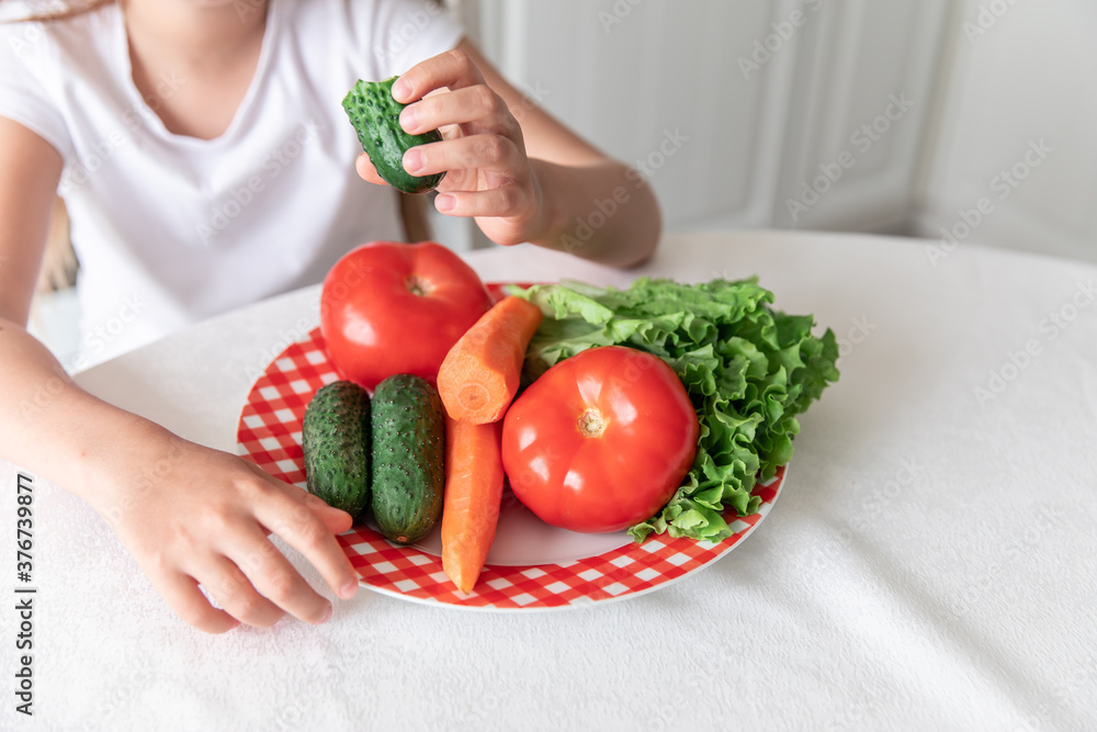 little girl eats vegetables in the kitchen. healthy food. vegetarianism. little girl eats vegetables in the kitchen. healthy food. vegetarianism.