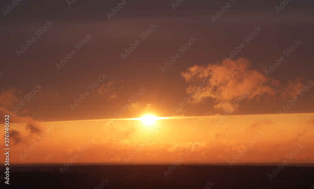 Bright orange sun at sunset with a clear horizon
