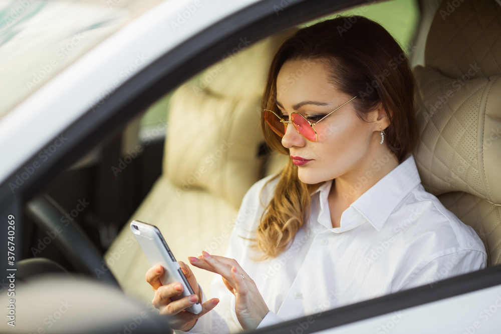 beautiful young woman driving a car with a mobile phone