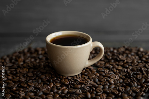 Cup of coffee with roasted coffee beans background. Mug of black coffee.