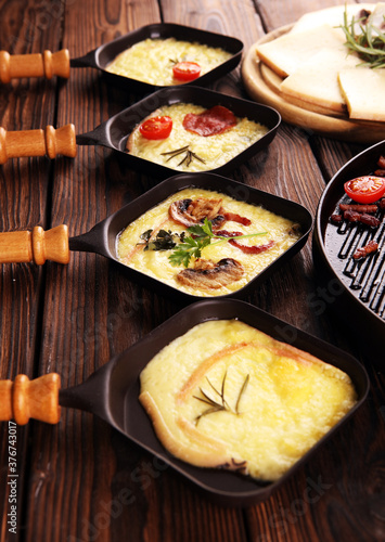 Canvas Print Delicious traditional Swiss melted raclette cheese served in individual skillets