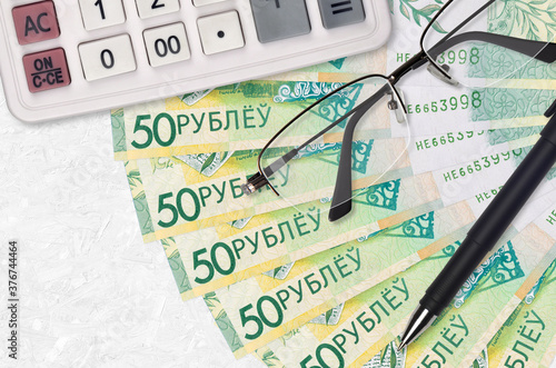 50 Belorussian rubles bills fan and calculator with glasses and pen. Business loan or tax payment season concept photo