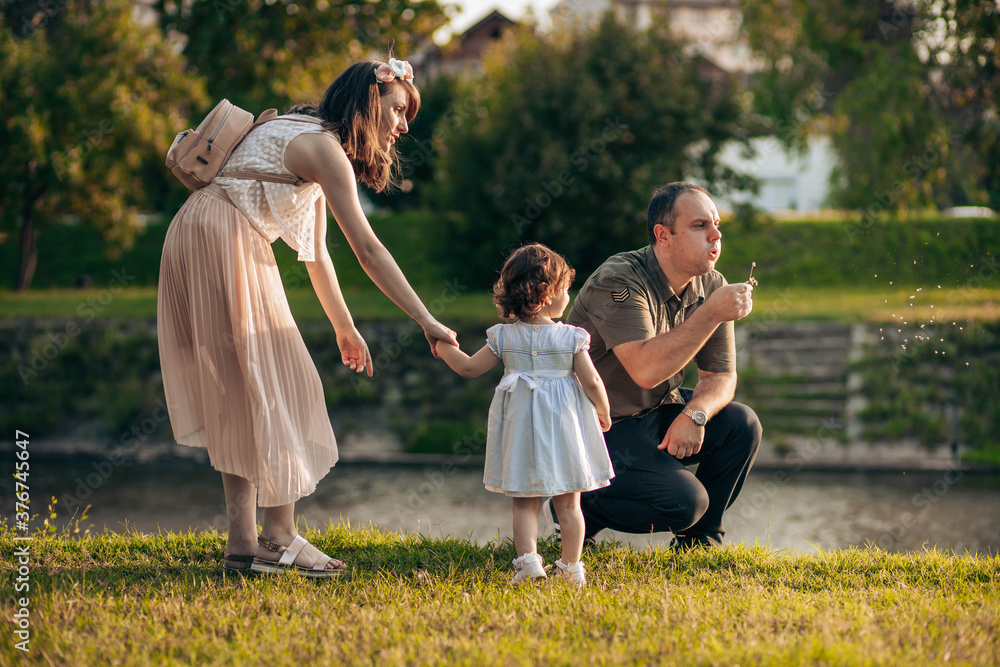 Naklejka premium Happy family, mother, father and little daughter have fun outdoors