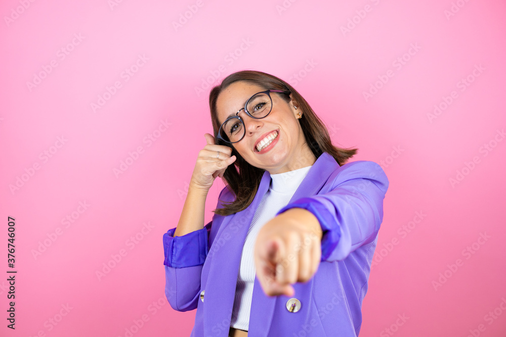 Young beautiful business woman over isolated pink background doing the “call me” gesture with her hands. Young beautiful business woman over isolated pink background doing the “call me” gesture with her hands.