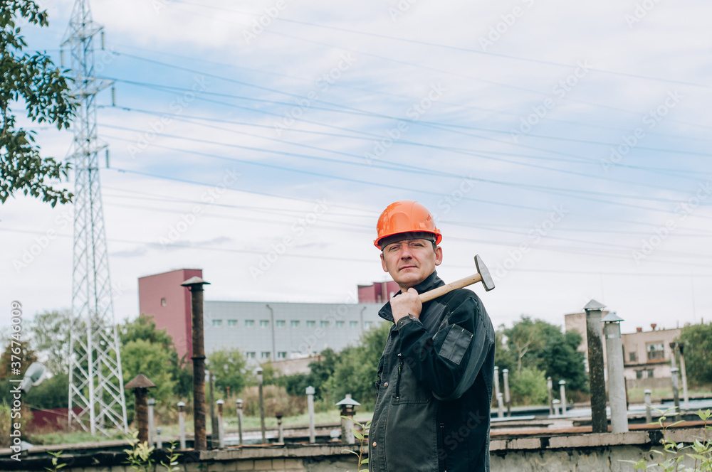 Construction worker writing on clipboard. Male engineer standing at electricity station Construction worker writing on clipboard. Male engineer standing at electricity station