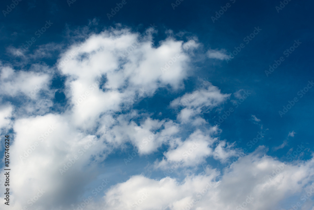 White cotton wool clouds on a sunny day. A continuous stream of clouds across the summer sky.