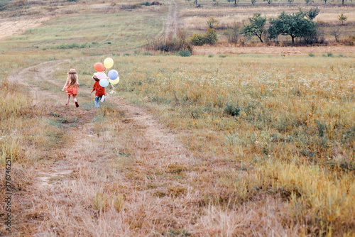 Cute child with balloons. Little girl and boy on a walk. Enjoy moment. Happy child in summer in nature. Child care. Child has summer joy.