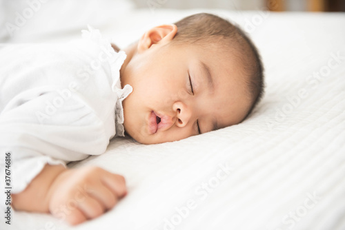 Newborn asian baby girl sleep on white bed relaxing feelgood happy. people health care concept.