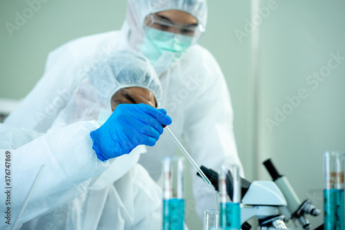 Asian medical scientist in protective white jumpsuit and glasses and face mask diagnosis virus with microscope in clinical laboratory