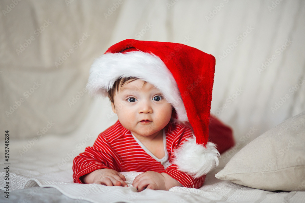 Smiling happy baby in christmas santa's hat and red overalls Smiling happy baby in christmas santa's hat and red overalls