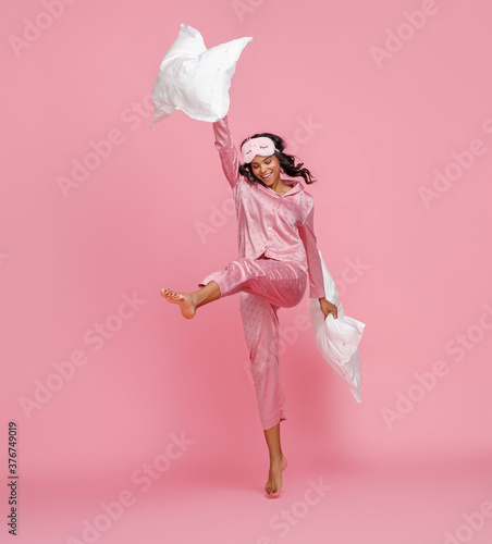 Young woman having fun with pillows. photo