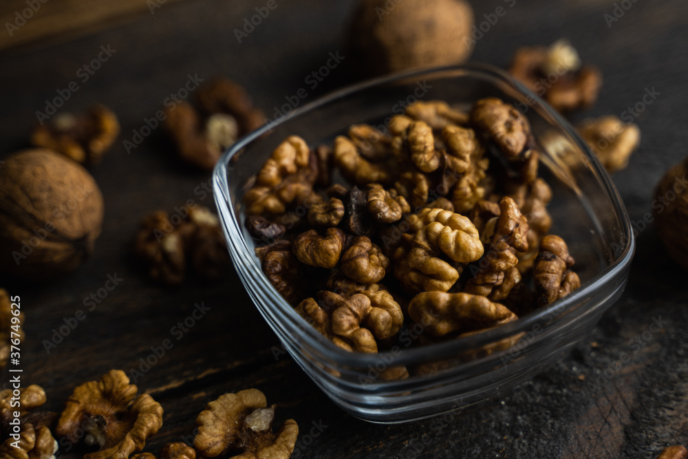 Walnut in a smale plate with scattered shelled nuts and whole nut which standing on a wooden vintage table. Walnuts is a healthy vegetarian protein nutritious food. Walnut on rustic old wood. Walnut in a smale plate with scattered shelled nuts and whole nut which standing on a wooden vintage table. Walnuts is a healthy vegetarian protein nutritious food. Walnut on rustic old wood.