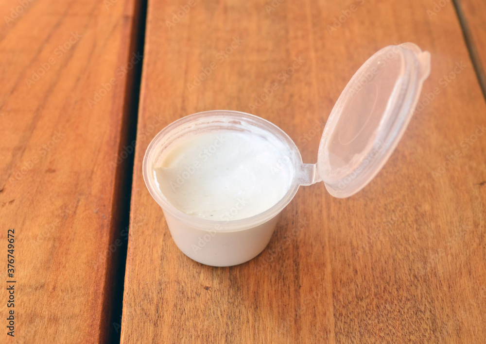 White cream in a plastic jar on a wooden background. White cream in a plastic jar on a wooden background.