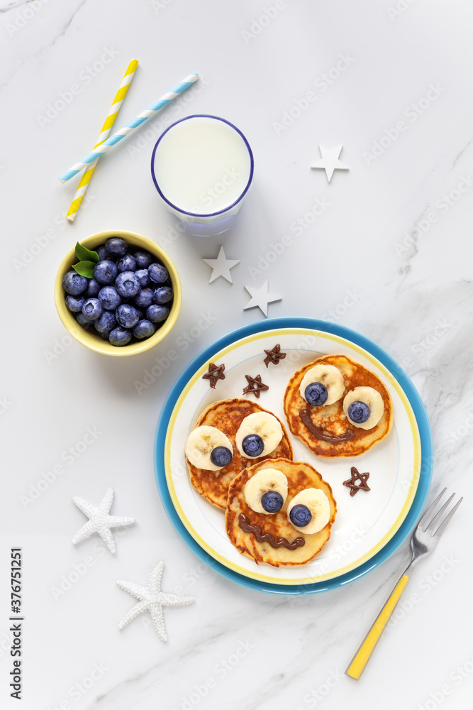 un food for kids - cute smiling faces on sweet pancakes for breakfast with bananas, fresh blueberries and blackberries. Creative cooking for children un food for kids - cute smiling faces on sweet pancakes for breakfast with bananas, fresh blueberries and blackberries. Creative cooking for children