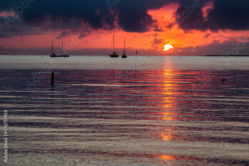 Sunrais on horizon  with boats and water photo