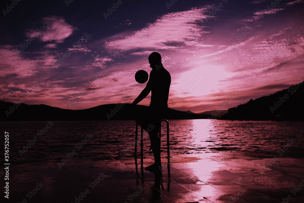 Silhouette of man playing football on the beach