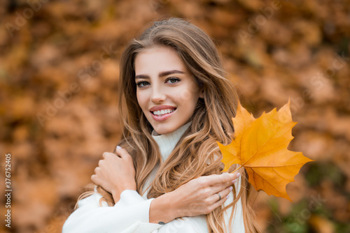 Autumn beauty and fashion. Woman fashion wodel with fall maple leaf outdoors.