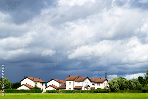 Wallpaper Mural A new cottage settlement with a flat green lawn. Nice little houses. Dark gray dramatic clouds. Rainy weather Riga, Latvia Torontodigital.ca