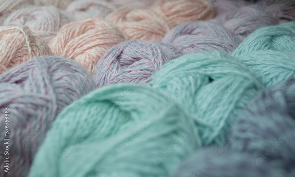 Close-up of skeins of lilac-pink thread, around-blurred skeins of pastel colors of green and blue. Thread background Close-up of skeins of lilac-pink thread, around-blurred skeins of pastel colors of green and blue. Thread background