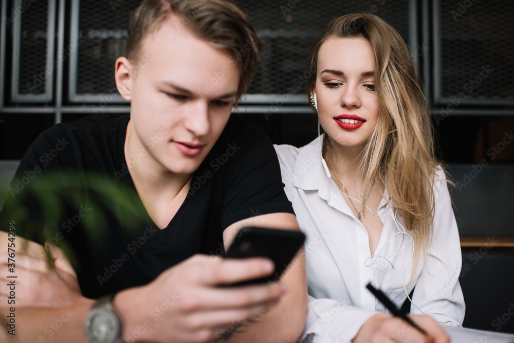 Trendy modern couple browsing smartphone in cafe Trendy modern couple browsing smartphone in cafe