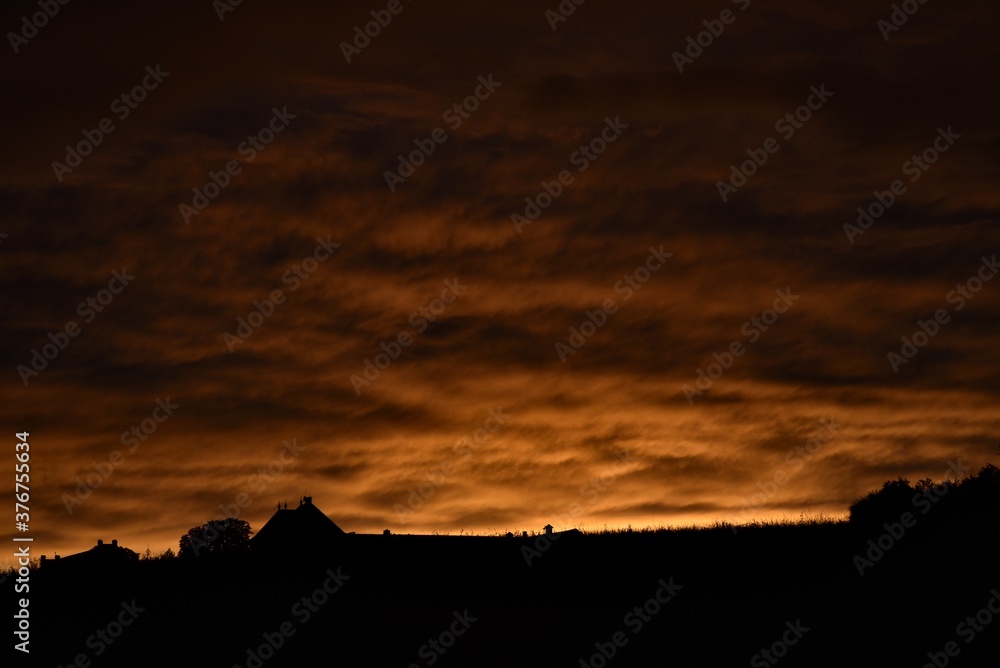 Dramatic colorful clouds at sunset, with a silhouette of a human dwelling. 08-22-2020, Middle Bohemia, Czech Republic.