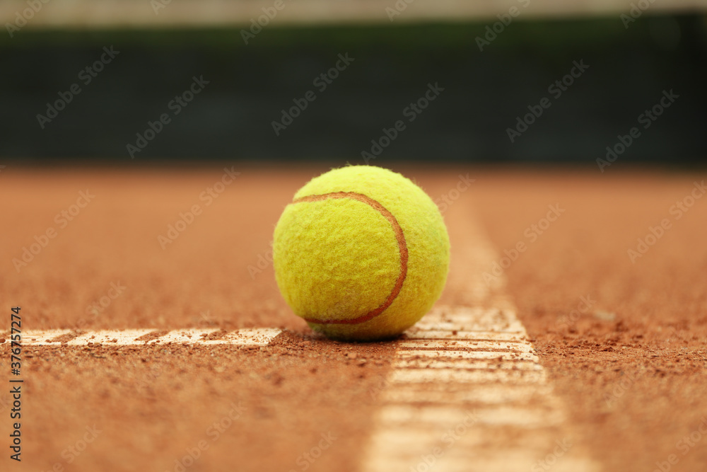 Light green tennis ball on clay court, close up