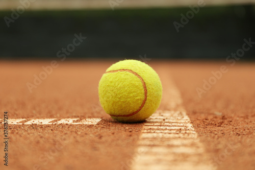Light green tennis ball on clay court, close up © Atlas