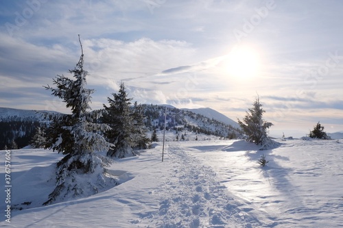 Beautiful winter mountain views at sunset during a snowshoe hike along the red ridge trail in the Low Tatras, Slovakia - trampled tracks in the snow around Sedlo pod Skalkou