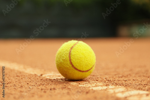 Light green tennis ball on clay court, close up © Atlas