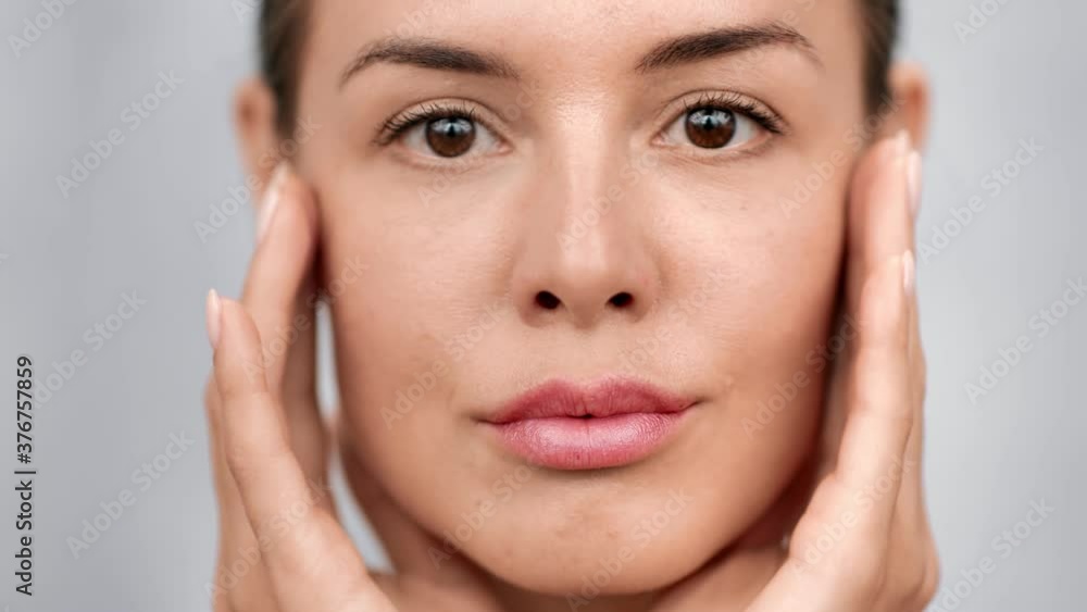Smiling woman applying moisturizer cream enjoying facial care. Close up shot on 4k RED camera Smiling woman applying moisturizer cream enjoying facial care. Close up shot on 4k RED camera