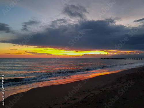 Sunset on the sea  red-orange sky with dark clouds and a piece of beach