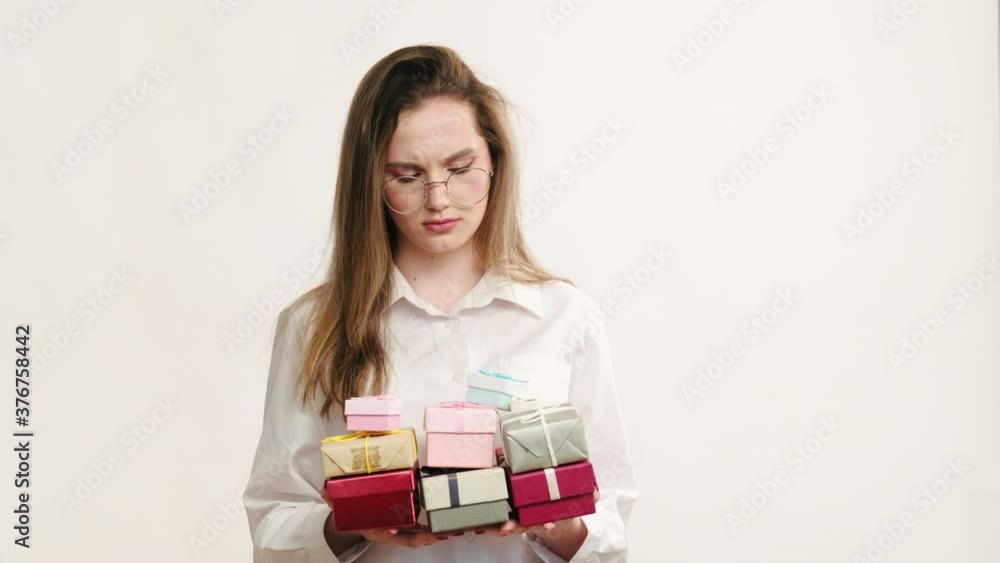 Bad surprise. Boring party. Disappointed annoyed business woman in glasses throwing away colorful gift boxes isolated on neutral copy space background. Surprise failure. Bad surprise. Boring party. Disappointed annoyed business woman in glasses throwing away colorful gift boxes isolated on neutral copy space background. Surprise failure.