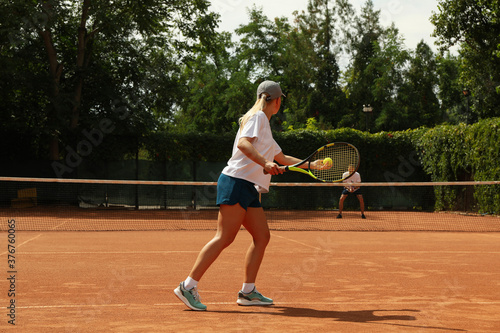 Two people playing tennis on clay court