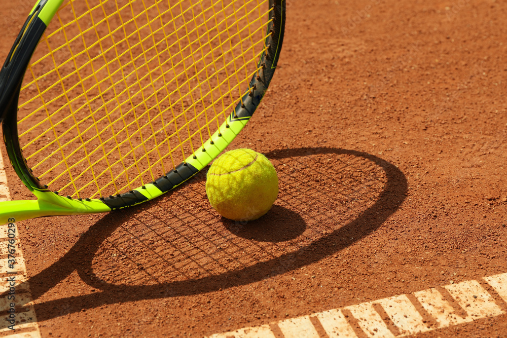 Tennis racquet and tennis ball on clay court