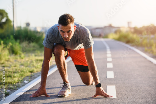 Sports man runner with smart watch in start position preparing to run