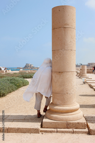 Person by column, roman ruins in ancient port city of Caesarea, Israel photo