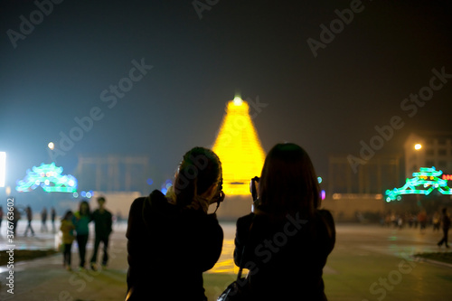 Two Chinese tourists taking photos of the illuminated pagoda in the centre of Sanjiang, Guangxi Provence, China photo