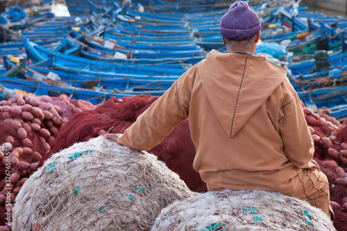 Local man sitting at fishing port, rear view, Essauira, Morocco photo