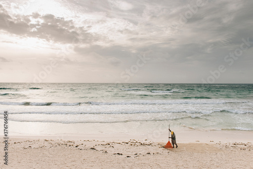 Local man raking sand on beach, Tulum, Mexico photo